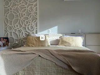 Quarto com cama grande e cabeceira decorativa em um ambiente claro.