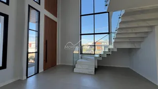 Vista interna de uma sala com grandes janelas e escadaria de mármore.
