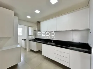Armários brancos e bancada escura de uma cozinha moderna.