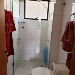 Banheiro com revestimento branco e piso cerâmico.