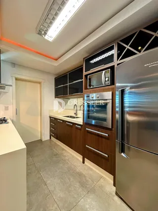 Vista da cozinha com armários de madeira e eletrodomésticos de aço inoxidável.