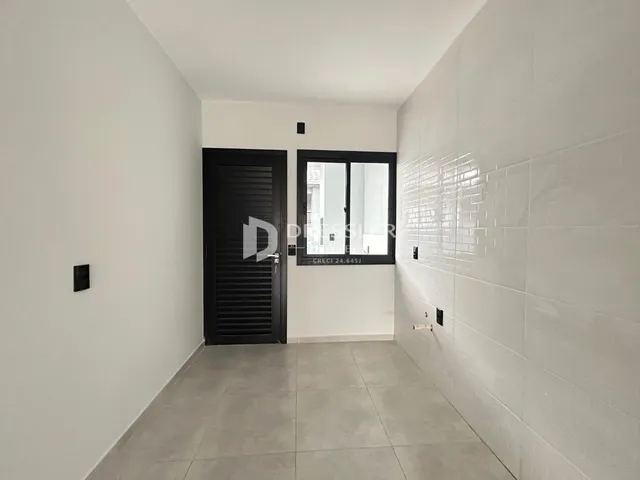 Corredor interno com paredes brancas e piso cinza claro.