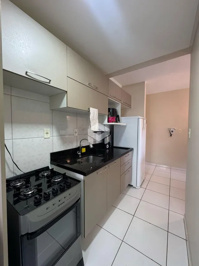 Cozinha moderna com armários brancos e bancada escura.