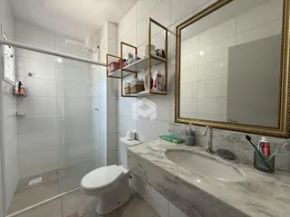 Imagem de um banheiro com revestimento branco e bancada de mármore.