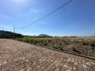 Vista de um pátio pavimentado com terraços e vegetação em uma área externa.