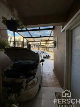 Foto da fachada de uma propriedade mostrando um carro estacionado sob uma cobertura.