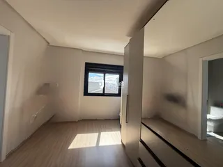 Interior de um cômodo com piso de madeira e janela.