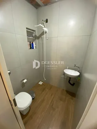 Foto de um banheiro interno com piso de madeira e louças sanitárias.