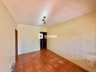 Foto de um cômodo interno com piso de ladrilho vermelho e paredes claras.