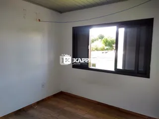 Foto interna de um cômodo com paredes brancas e piso de madeira.