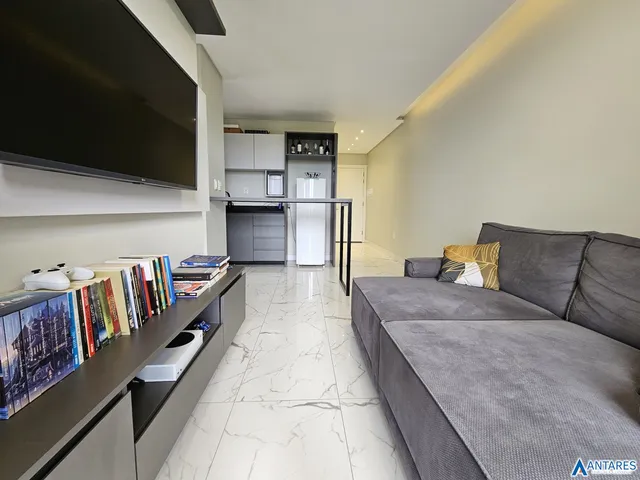 Sala de estar moderna com sofá cinza e piso de porcelanato claro.