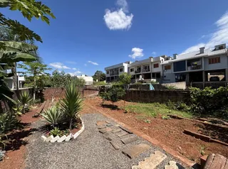 Jardim externo com vegetação e caminho de cascalho.