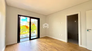 Vista interna de uma sala com piso de madeira e porta de vidro que dá para o exterior.