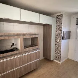 Foto interna da cozinha com armários brancos e piso de madeira clara.