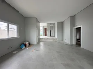 Vista interna de um espaço amplo e em construção com piso de concreto.