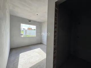 Vista interna de um ambiente com paredes brancas e piso de concreto.