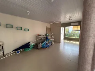 Ambiente interno de uma sala ampla com piso de cerâmica e paredes brancas.