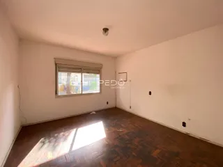 Ambiente interno de uma sala com piso de madeira e janela.
