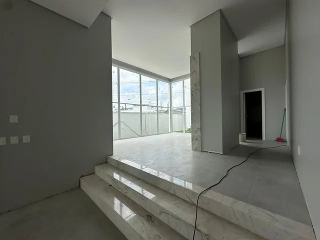 Espaço amplo com piso de concreto polido e grandes janelas que dão vista para o exterior.