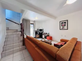 Sala de estar com escadaria e sofá em um imóvel no Brasil.
