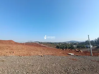 Paisagem de terra avermelhada com vista para colinas ao fundo.