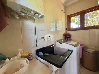 Foto de um banheiro com azulejos brancos e uma máquina de lavar roupa.