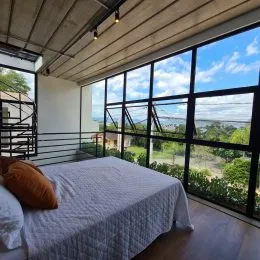 Foto de um quarto com cama e grande janela com vista para a paisagem.