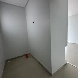 Vista de um corredor interno com paredes brancas e piso claro.