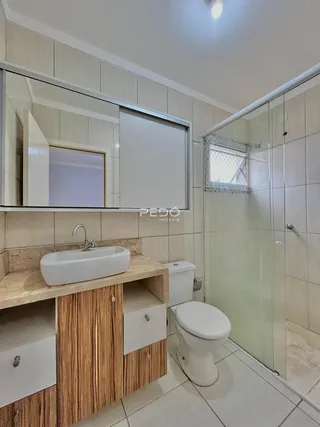 Foto de um banheiro com revestimento cerâmico e box de vidro.