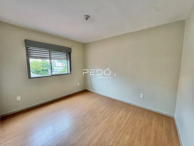 Ambiente interno de uma sala com piso de madeira clara e paredes neutras.