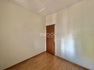 Vista interna de um corredor com piso de madeira e porta de madeira.