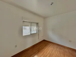 Sala de um imóvel com piso de madeira e janela.