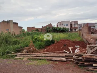 Vista externa de um terreno com vegetação e pilhas de madeira no primeiro plano.