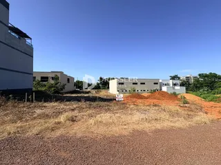 Vista externa de uma propriedade com terreno seco e vegetação rasteira em primeiro plano.