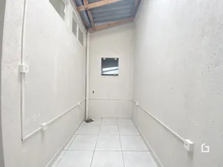 Corredor interno de uma residência com piso de cerâmica branca.