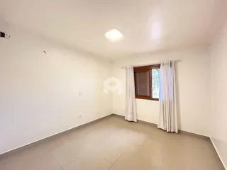 Ambiente interno de uma sala ampla com paredes brancas e piso claro.