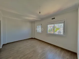 Sala de estar com piso de madeira clara e janela.
