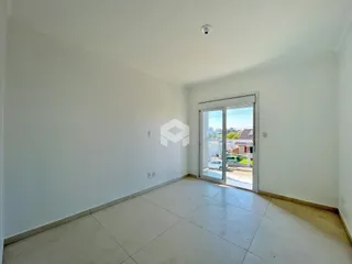Uma sala de estar ampla com piso de cerâmica clara e porta de vidro.