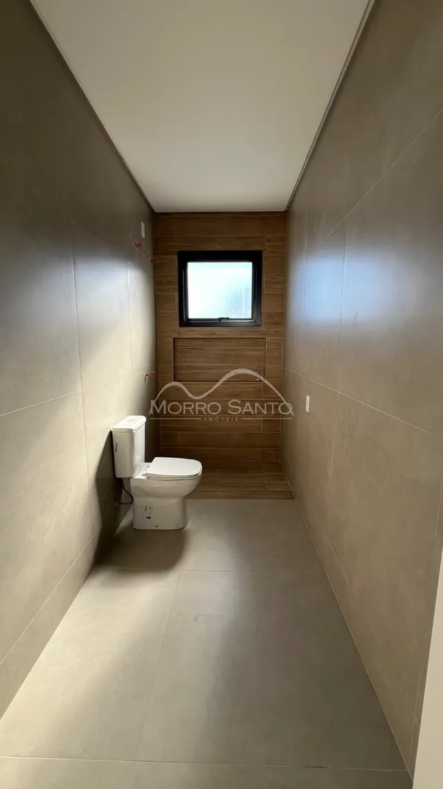 Corredor estreito com um vaso sanitário branco e parede de madeira.