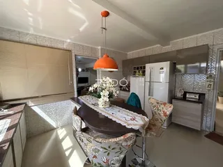 Foto de uma sala de jantar com móveis de madeira e cozinha moderna.