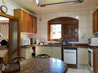 Vista da cozinha com armários de madeira e bancadas de granito.