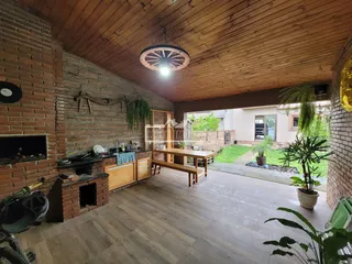 Sala de estar com paredes de tijolo aparente e teto de madeira em uma casa no Brasil.