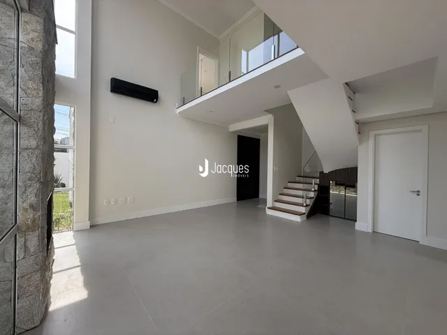 Ambiente interno moderno com pé direito alto e piso claro.