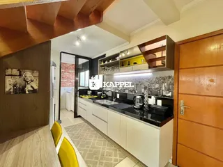 Foto interna da cozinha com armários brancos e bancadas escuras.