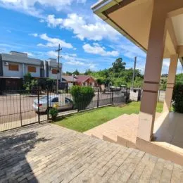 Deck de madeira externa com área verde ao fundo.