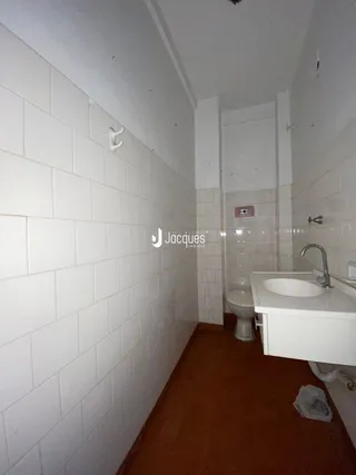 Corredor interno com paredes brancas e piso de madeira.