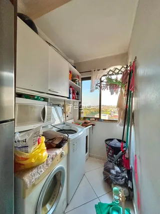 Interior de uma área de serviço com armários brancos e máquina de lavar roupa.