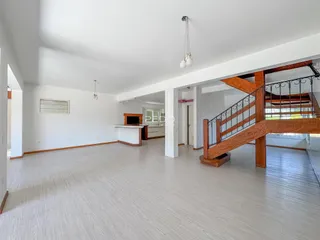 Ambiente interno de uma sala de estar com piso claro e escadaria de madeira.