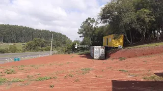 Vista externa de um terreno com vegetação e solo avermelhado.