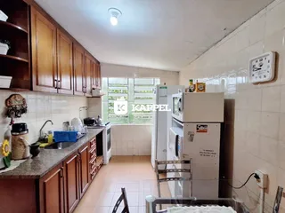 Foto interna de uma cozinha com armários de madeira e eletrodomésticos.